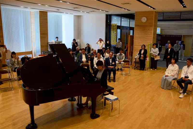 寄贈式後、豊永昭子さんのピアノ演奏に聞き入る人吉市職員ら＝10日、同市