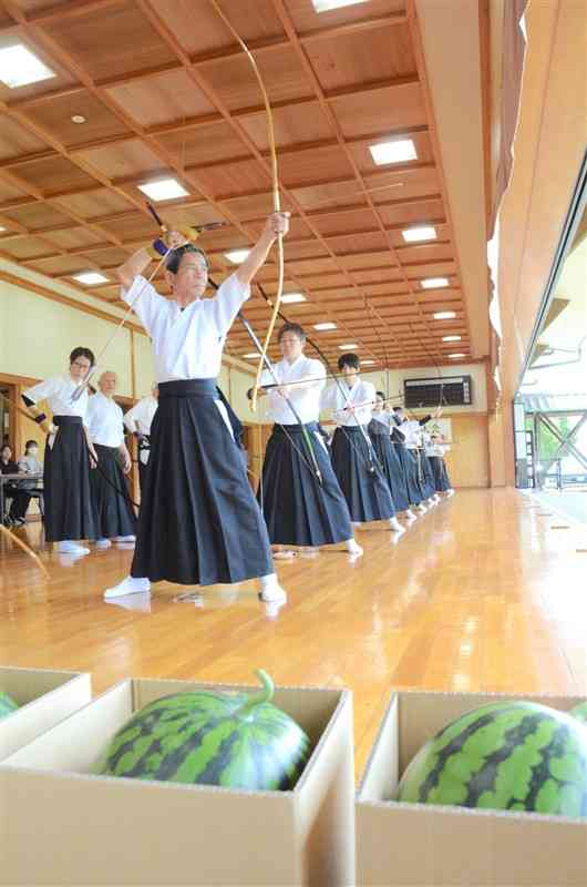 植木町特産のスイカとメロンを目指して弓を引く参加者ら＝11日、熊本市北区