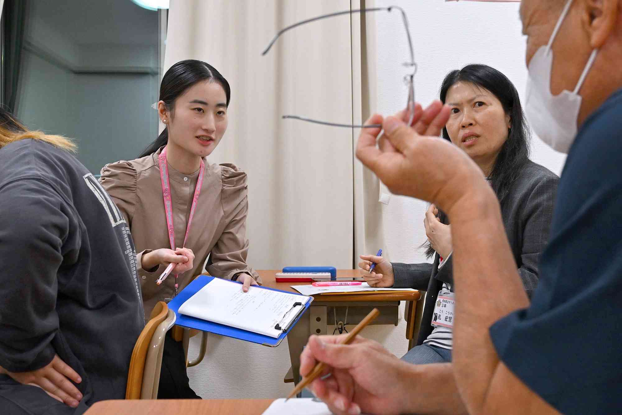 熊本県立ゆうあい中の授業で、生徒と課題について話し合う上野史央里記者（左）＝10日、熊本市中央区（小野宏明）