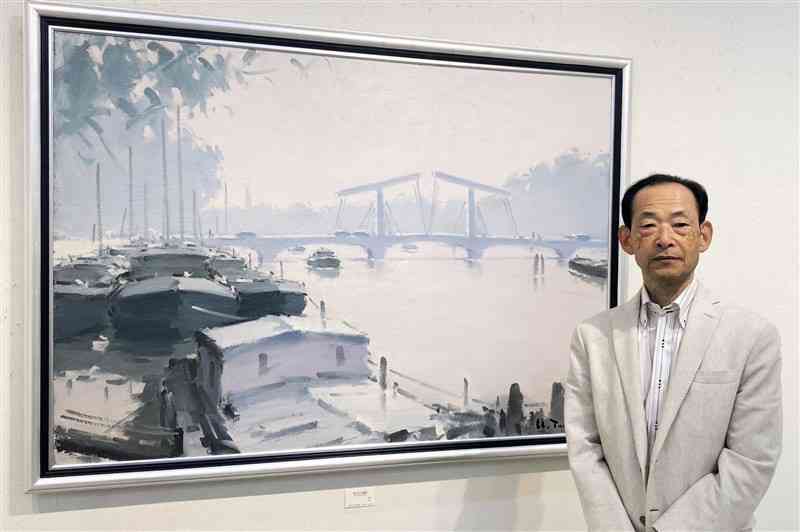 オランダ・アムステルダムの風景を描いた「雨上がりの運河」の前に立つ歳嶋洋一朗さん＝14日、東京・銀座
