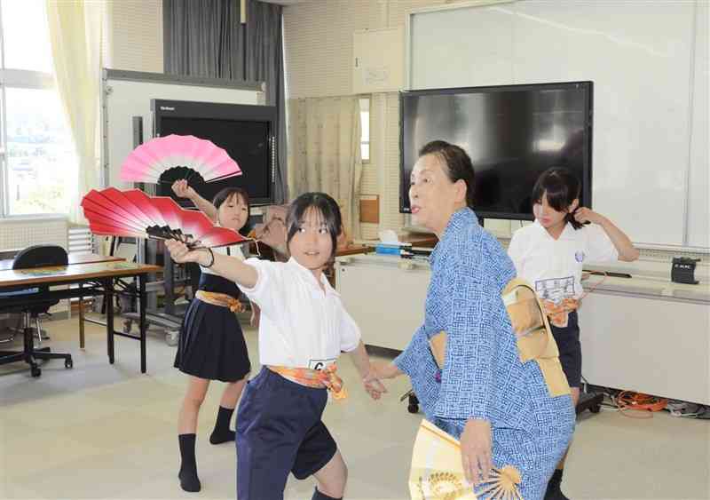 菱形小「民舞クラブ」の児童らに踊りを教える藤間きみ藤さん（右から2人目）＝14日、熊本市北区