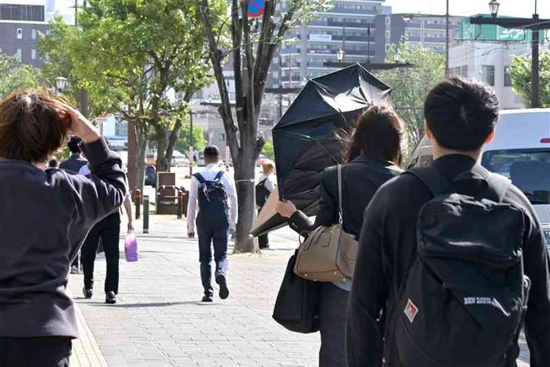 強風の中を通勤、通学する人たち＝16日午前8時50分ごろ、熊本市西区のJR熊本駅前（谷川剛）
