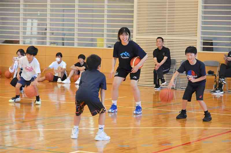 東京羽田ヴィッキーズの選手（中央）からドリブルのこつなどを学ぶ子どもたち＝18日、天草市