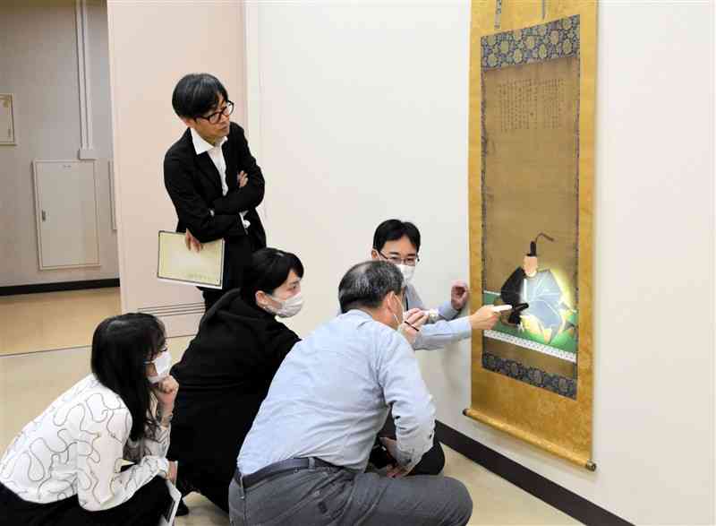 過去に修復した細川家ゆかりの作品を鑑賞する参加者の男性（手前）ら＝19日、熊本市中央区