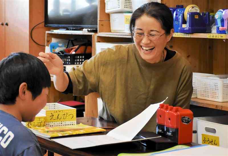 児童の宿題を見ながら談笑する学童保育支援員の大谷昌江さん＝17日、産山村