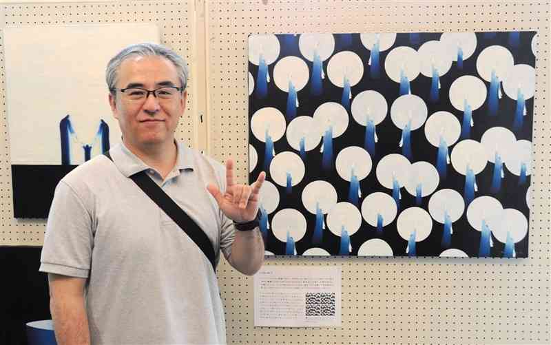 展示作品とともに、手話で「I　LOVE　YOU」を示す乘富秀人さん＝20日、大津町