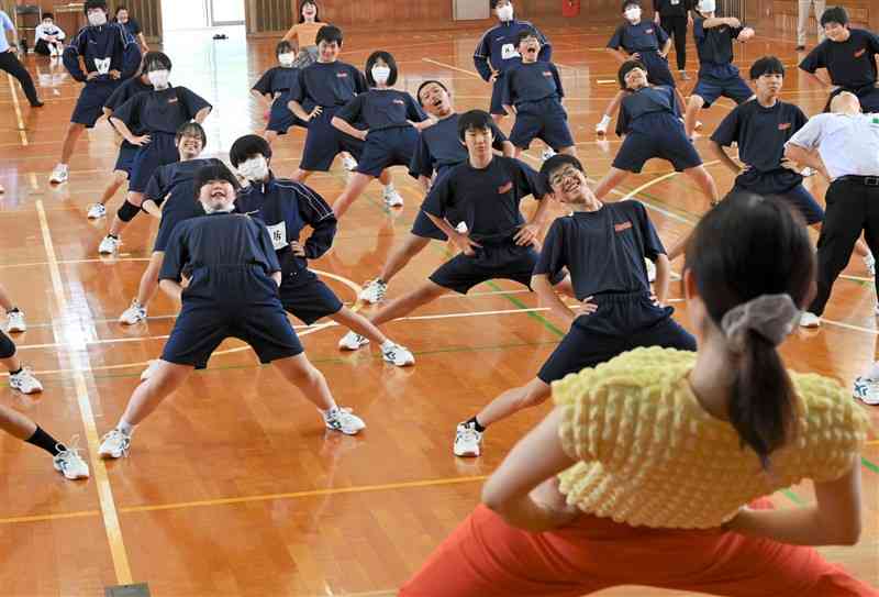 劇団員（手前）の動きに合わせて体を動かす生徒たち＝23日、山鹿市