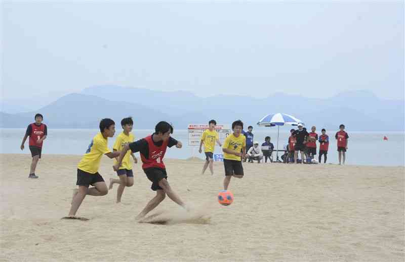 砂浜を駆け回りゴールを狙う中学生の参加者ら＝26日、芦北町