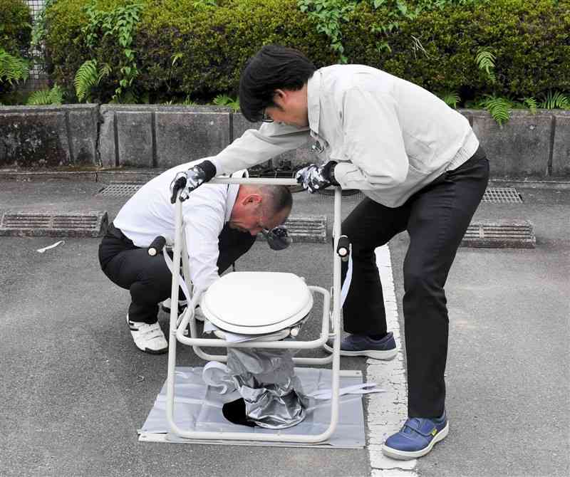 マンホールトイレの設置を実演する熊本市上下水道局の職員＝22日、市東部浄化センター