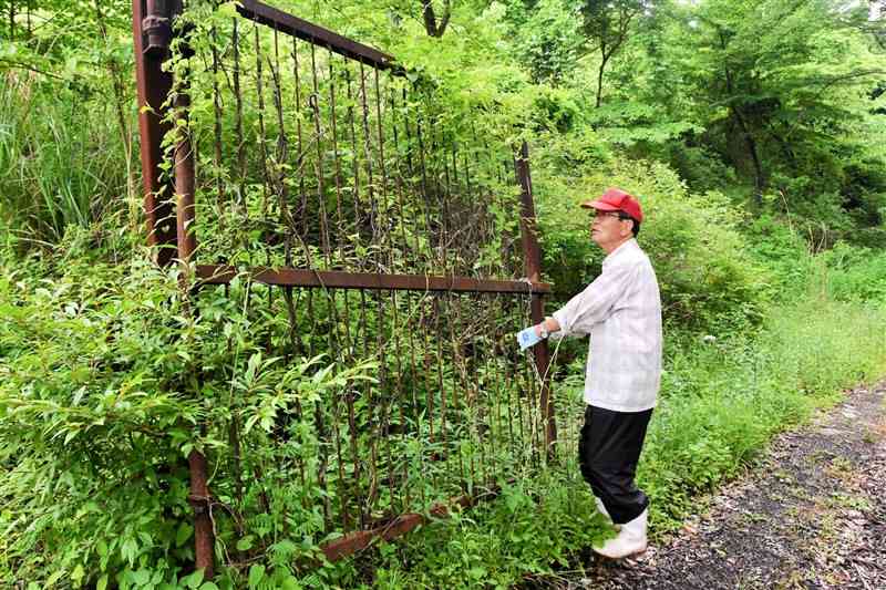 オウム真理教道場跡地に残る鉄扉の前に立つ阿南忠治さん＝5月27日、阿蘇市波野