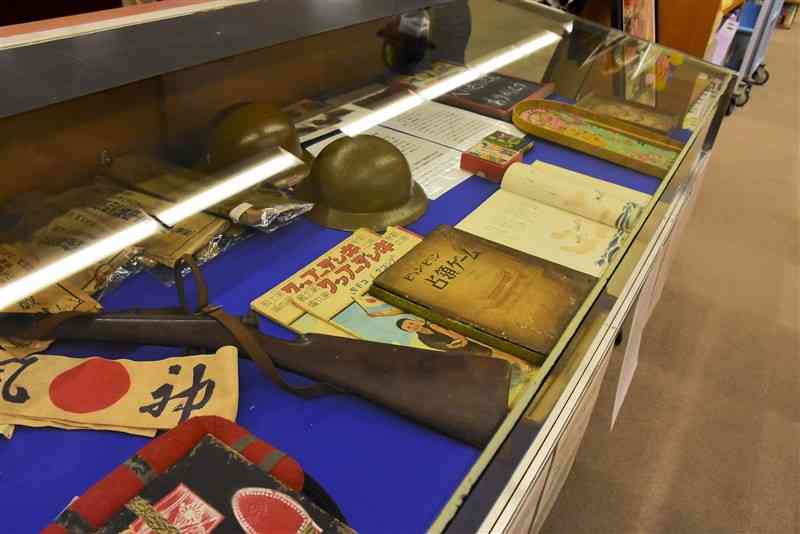 熊本市立図書館で開かれている戦時資料の展示会で並べられた戦時下のおもちゃや絵本＝4日、同市中央区