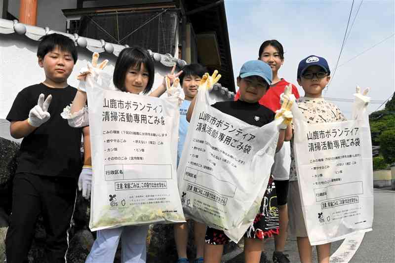 非食用米を活用したごみ袋を手に、清掃活動する子どもたち＝2日、山鹿市