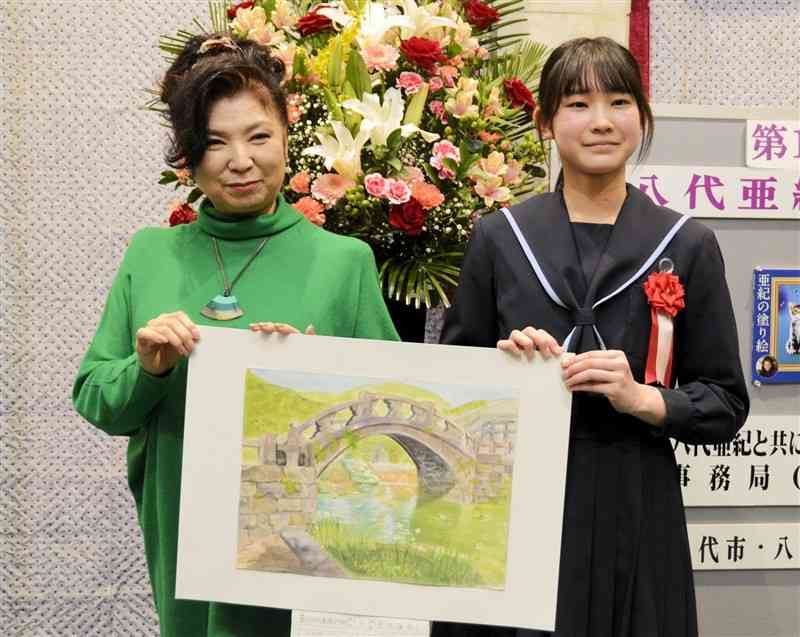 八代亜紀絵画コンクールの大賞受賞者を表彰する八代さん（左）＝2023年3月、八代市
