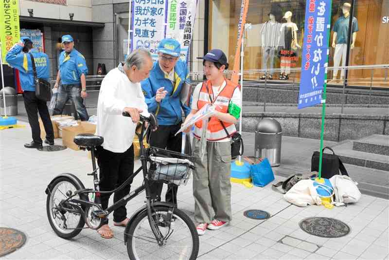 通行人に啓発チラシを手渡し、鍵かけの徹底を呼びかける防犯キャンペーンの参加者（右）＝9日、熊本市中央区