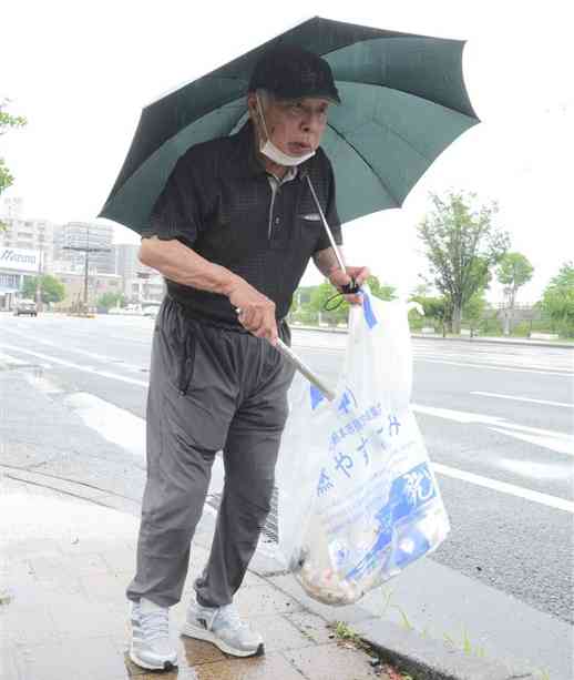 トングで熊本駅周辺のごみを拾う矢邉義興さん＝10日、熊本市西区