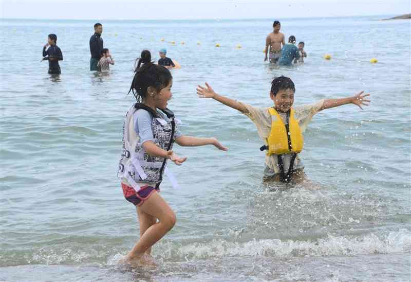 白鶴浜海水浴場の波打ち際で元気に遊ぶ子どもたち＝16日、天草市