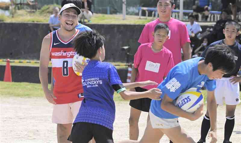 中学生にパスを指導する流大選手（左）＝16日、荒尾市