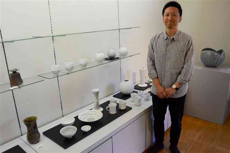 白磁に黒のドットが印象的な黒釉象嵌の鉢などを出品した江上晋さん＝18日、熊本市中央区