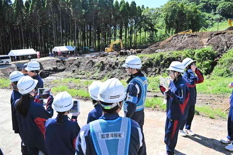砂防ダムの建設箇所にタブレットをかざして、完成後のイメージを見る高森高の生徒ら＝18日、高森町