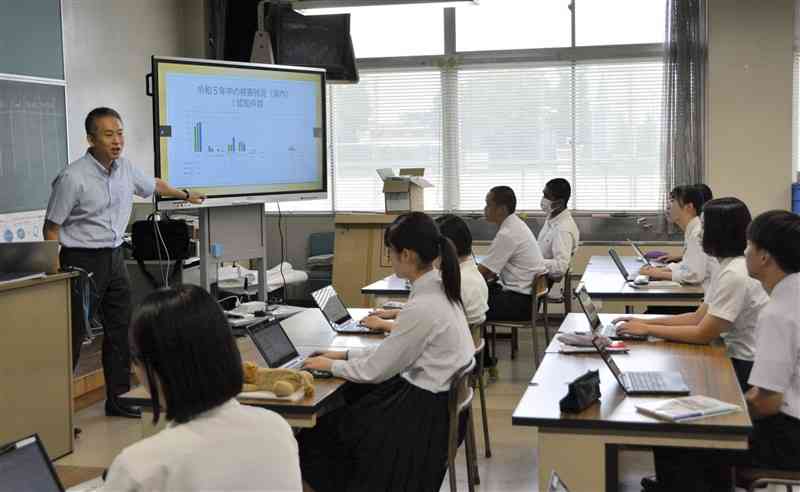 特殊詐欺の手口などについて生徒に説明する熊本東署の警察官（左）＝20日、熊本市中央区