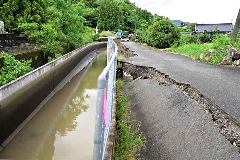 長さ約500メートルにわたって陥没した八代市道と、土台が傾き通水できなくなった農業用水路「不知火幹線水路」＝21日、八代市東片町