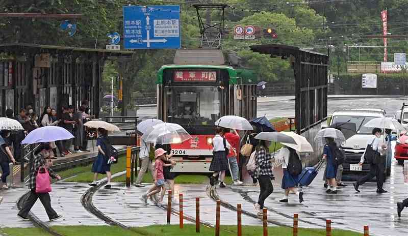 雨の中、傘を手に交差点を渡る買い物客ら＝27日午後0時半ごろ、熊本市中央区（石本智）