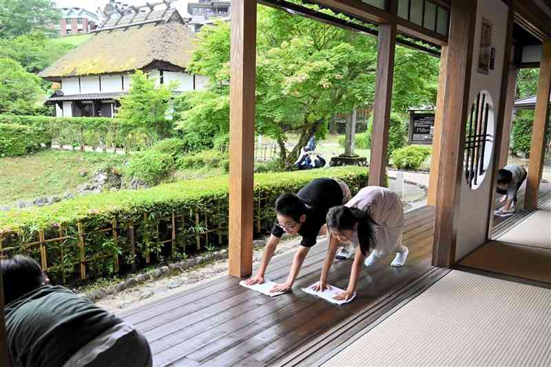 北里柴三郎記念館の「貴賓館」を雑巾がけする子どもたち。奥は柴三郎の生家の一部＝6月15日、小国町