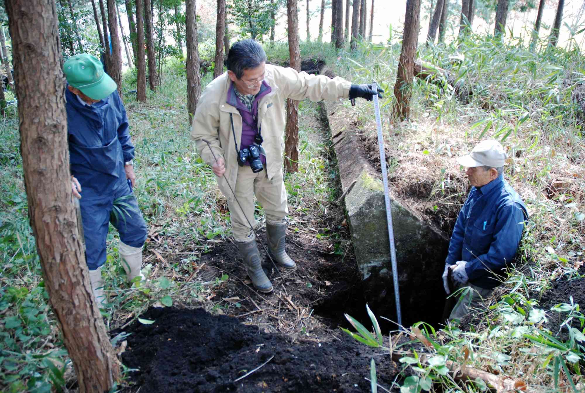 あさぎり町で木製有蓋掩体壕の基礎を調査する筆者（中央）ら＝2008年3月