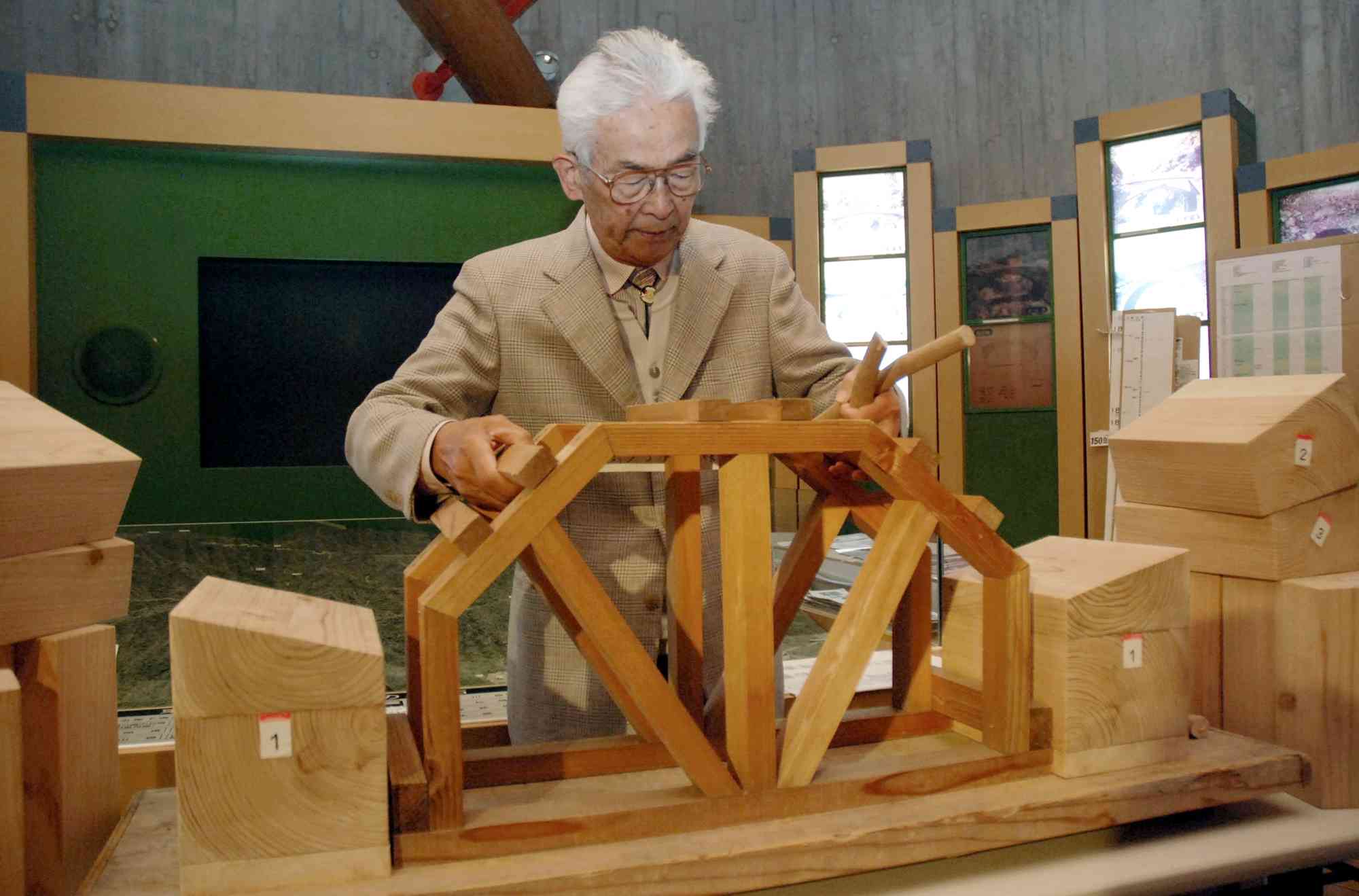 木の模型を使い、石橋の架け方を説明する東陽石匠館長時代の上塚尚孝さん＝2013年4月