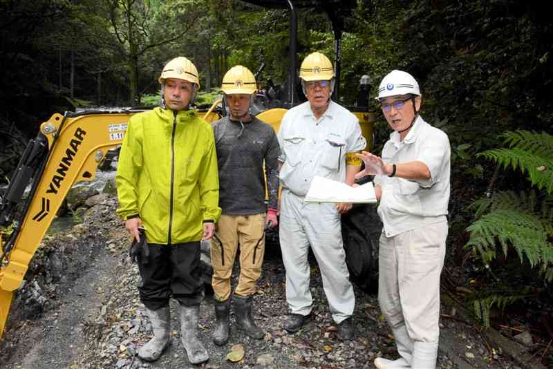 豪雨で被災した林道の復旧現場で働く元八代市建設部長の潮﨑勝さん（右）＝6月25日、八代市坂本町