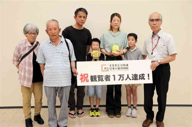 天草市立御所浦恐竜の島博物館で来場者1万人目となった家族ら＝6月29日、天草市