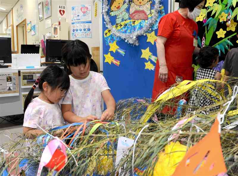 願いを書いた短冊をササに飾る姉妹＝6月30日、熊本市中央区