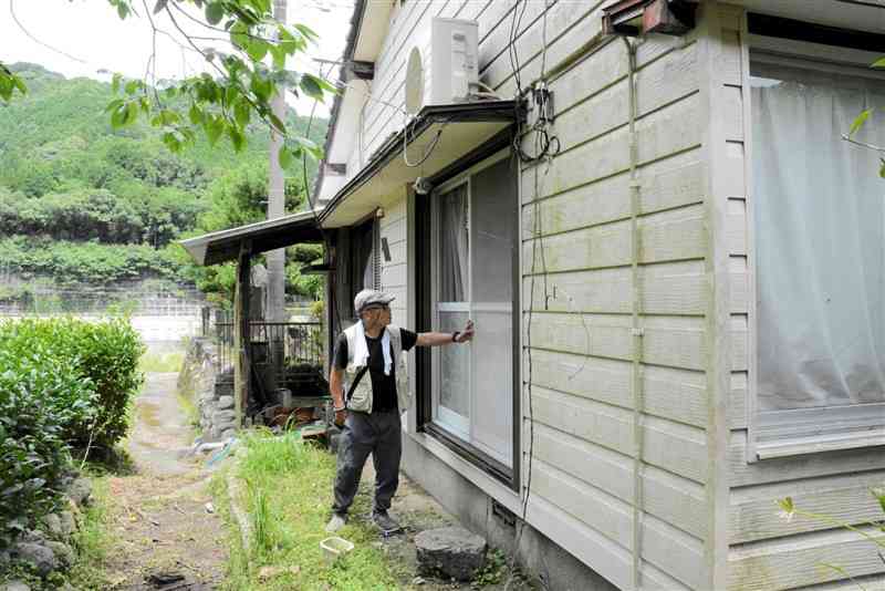 宅地かさ上げの対象となった自宅を見つめる中西敏明さん＝6月30日、八代市坂本町