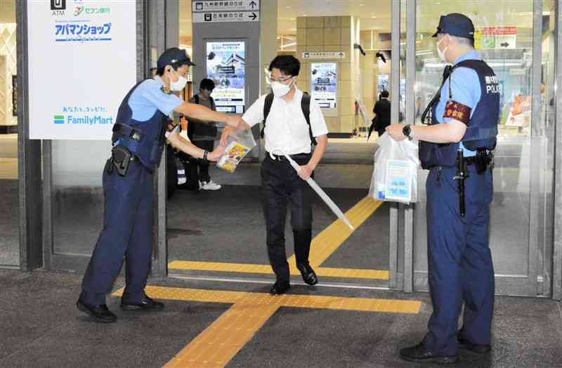 JR熊本駅の利用者にリーフレットを配り、痴漢や盗撮の被害防止や通報への協力を呼びかける警察官＝1日、熊本市西区