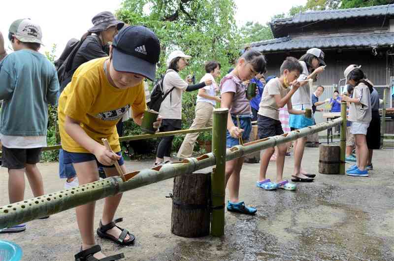 地元住民が竹で作った手作りの流し台で、そうめん流しを体験＝2023年9月、高森町