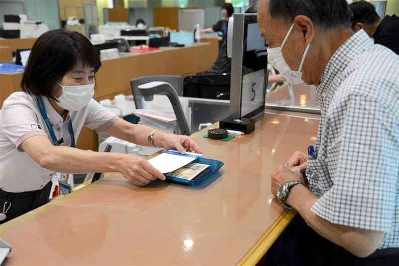 両替した新紙幣を肥後銀行本店の窓口で受け取る客＝3日午前9時過ぎ、熊本市中央区