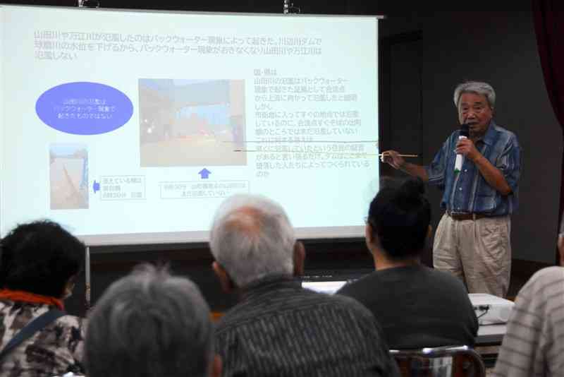 熊本豪雨当日の写真を示しながら、山田川など球磨川の支流が氾濫した様子を説明する木本雅己さん＝4日、人吉市