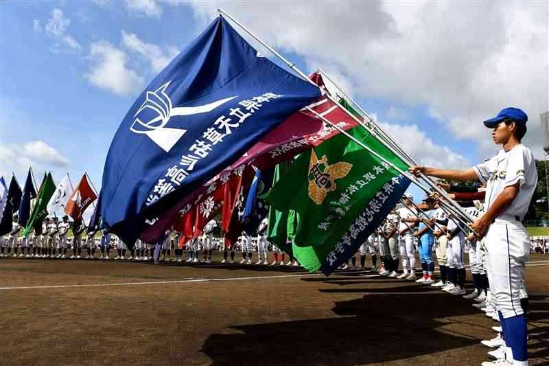 青空の下、開会式の選手宣誓で校旗を掲げ整列する各校の選手たち＝6日午前、熊本市中央区のリブワーク藤崎台球場（上杉勇太）