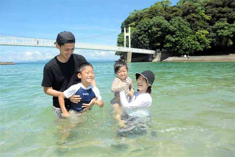 湯の児海水浴場で水遊びを楽しむ家族連れ＝7日、水俣市