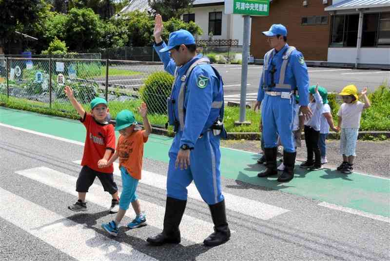 牛深署と県警交通機動隊が開いた交通安全教室で、道路を安全に渡る方法について保育園児に指導する警察官＝6月12日、天草市