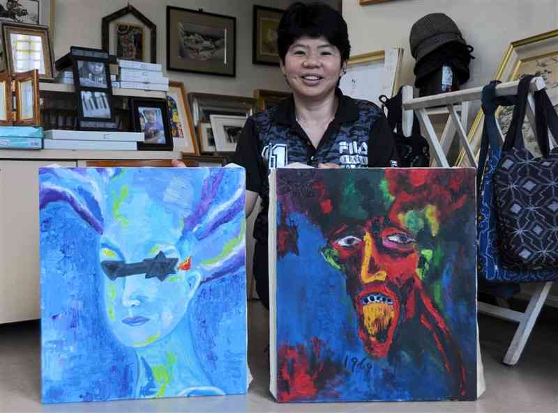 作品を持つ吉田紀子さん。左は、統合失調症と診断された思いを描いた作品。右は、20代のころに描いた性別や年齢が不詳の人物＝6日、人吉市