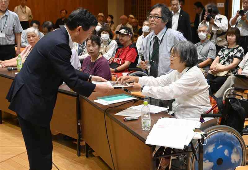 伊藤信太郎環境相（左）に資料を手渡す水俣病被害者互助会の会員＝8日午後2時25分ごろ、水俣市のもやい館（小野宏明）