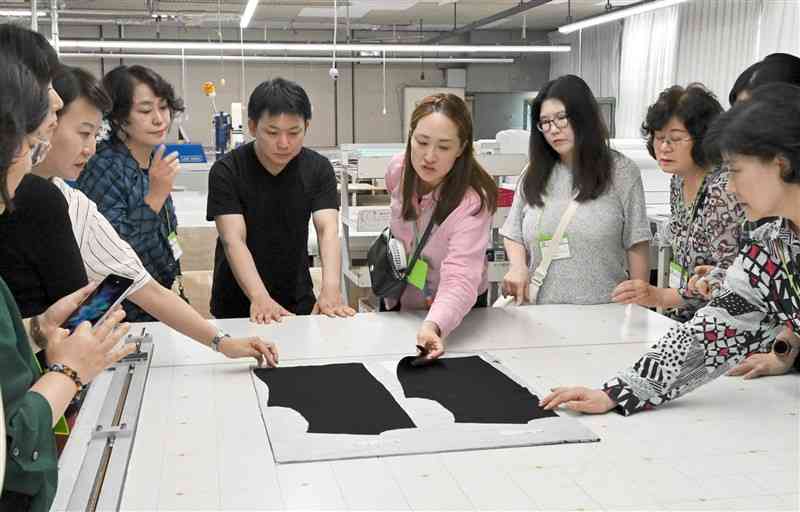 ラ・モードの作業現場を視察する韓国衣類産業学会のメンバーたち＝9日、山鹿市