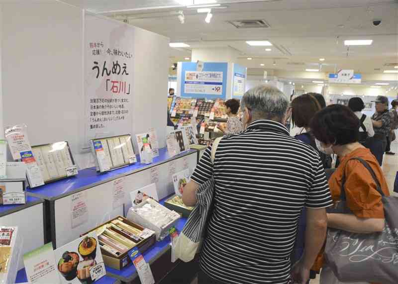 鶴屋百貨店が能登半島地震の復興応援で設けたコーナーで、石川県の商品を選ぶ来店客＝6月、熊本市中央区