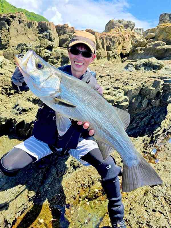 70センチ超のヒラスズキを重たそうに抱える山﨑真琴さん＝天草市牛深町の沖磯