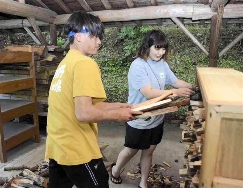 キャンプ場で使うまきを整理する渕田さん（右）と溝辺さん＝6月、五木村