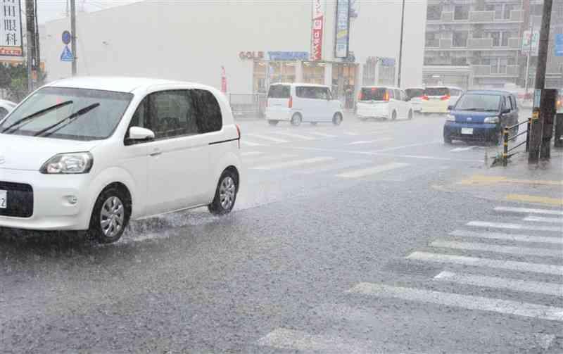 雨の中、水しぶきを上げて走る車＝14日11時半ごろ、熊本市中央区