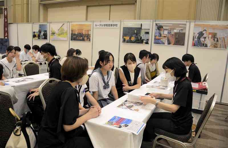 学校生活などに関する説明を聞く中学生と保護者ら＝15日、熊本市中央区