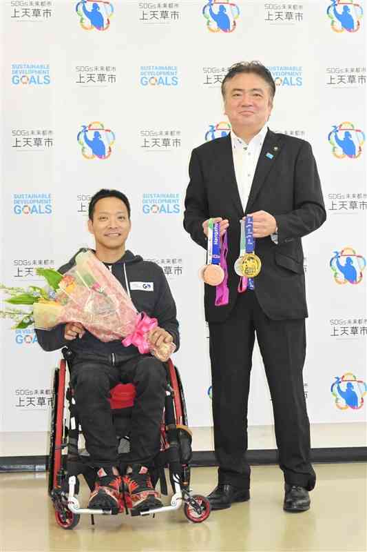 堀江隆臣市長（右）に、パリ・パラリンピック出場への意気込みを語った藤田道宣選手。直近1年間で獲得したメダルも披露した＝16日、上天草市