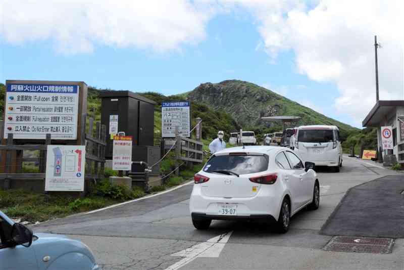 阿蘇中岳の噴火警戒レベルが1に引き下げられ、有料道路のゲート前を次々に通過する車の列＝19日、南阿蘇村